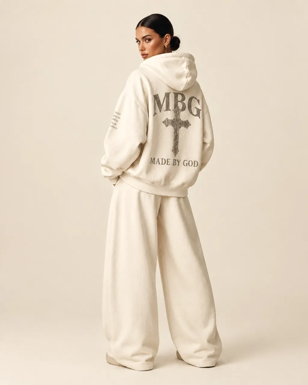 Woman wearing an ivory MBG hoodie and joggers in a cream studio